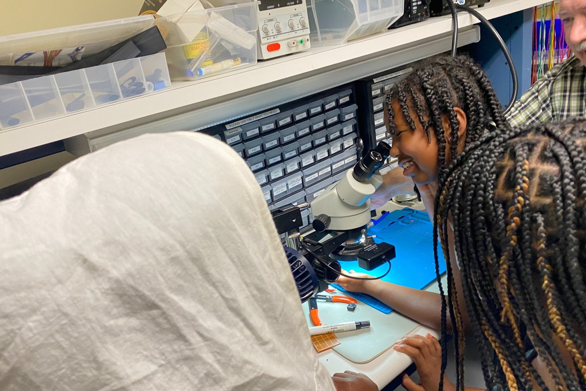 Prince Academy student looking through a microscope during biological sciences exploration